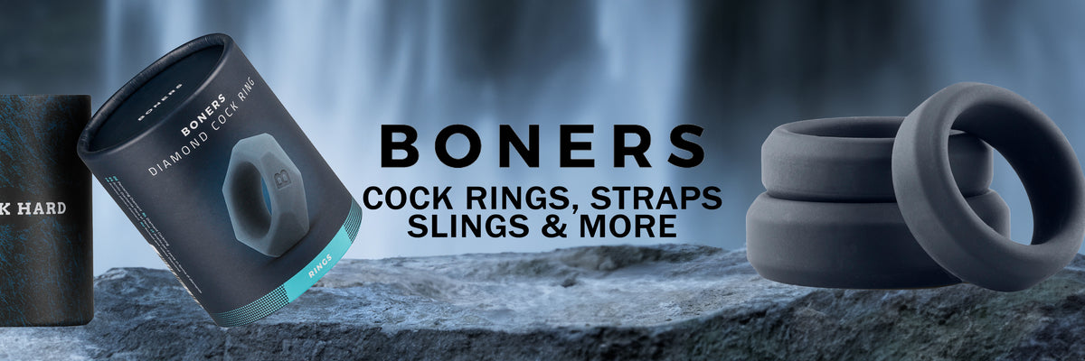 Promotional banner for 'BONERS' showing dark gray silicone cock rings, a black strap, and a cylindrical container on a rock with a blurred waterfall background. Text reads 'BONERS COCK RINGS, STRAPS SLINGS & MORE'.