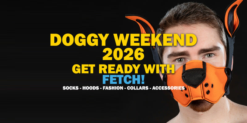 A man wearing an orange and black dog muzzle mask with attached orange ear-like accessories, against a black background with large yellow text reading 'DOGGY WEEKEND 2026 GET READY WITH FETCH!' and smaller text listing socks, hoods, fashion, collars, and accessories.