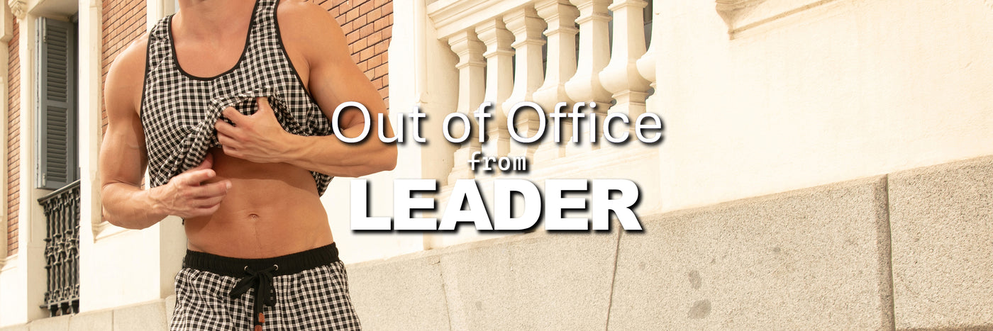 Man in checkered tank top and shorts standing in front of a building with 'Out of Office from LEADER' text.