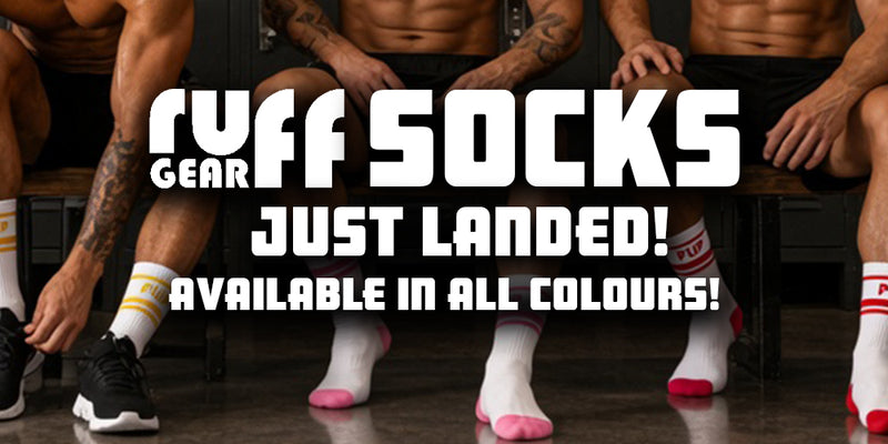 Promotional banner for Ruff Socks Gear showing several men sitting on a bench in a locker room setting, wearing various colored socks and athletic shoes. Large white text in the center reads 'RUFF SOCKS GEAR JUST LANDED! AVAILABLE IN ALL COLOURS!'.